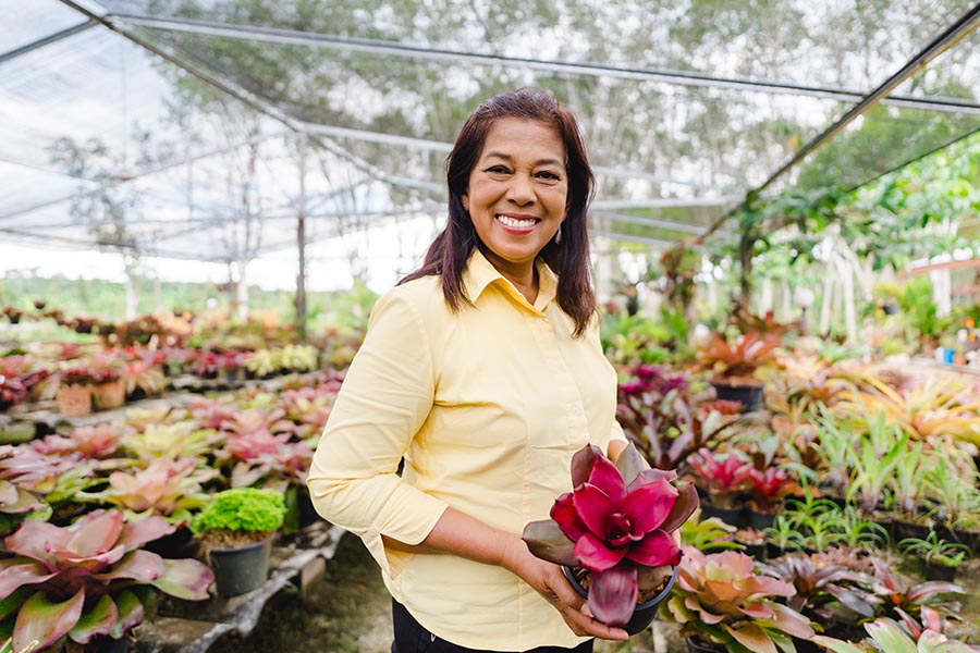 Specialized Business Insurance - Woman Shows off a Beautiful Plant in a Large Greenhouse